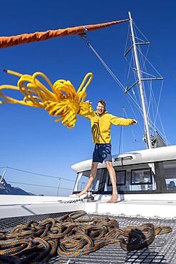 Sailor throws a yellow rope towards the camera, sailing on a sailing catamaran, Kos, Dodecanese, Greece, Europe