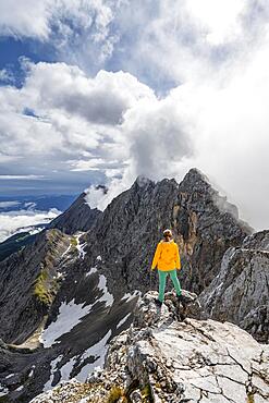 Hiker on a summit, Westliche Toerlspitze, mountains in dramatic clouds, Wetterstein Mountains, Garmisch-Partenkirchen, Bavaria, Germany, Europe