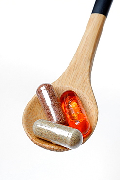 Capsules with food supplement and omega-3 fatty acid in wooden spoon