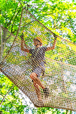 Boy climbing in a net in the climbing forest and high ropes course, Potsdam Adventure Park, Potsdam, Brandenburg, Germany, Europe