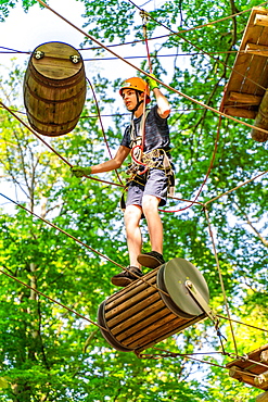 Boy on a floating barrel in the climbing forest and high ropes course, Potsdam Adventure Park, Potsdam, Brandenburg, Germany, Europe