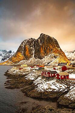 Winter Scandinavian landscape with illuminated red houses, sea, mountains, snow, Hamnoy, Nordland, Lofoten, Norway, Europe