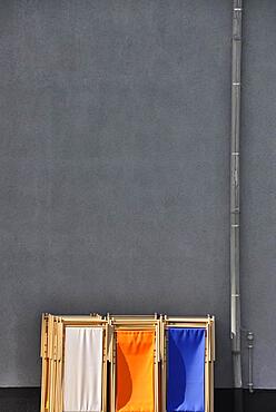 Grey wall with downpipe from gutter and coloured deck chairs in park, Cologne, Germany, Europe