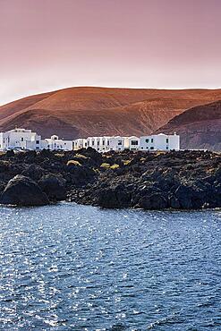 White houses on rocky lava coast, black volcanic rock, evening sky, Orzola, Lanzarote, Spain, Europe