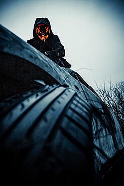 The Purge mask on a car wreck, in the morning with great light, Frankfurt am Main, Hesse, Germany, Europe