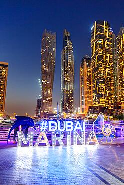 Dubai Marina Logo and Harbour Skyline Architecture Luxury Holiday in Arabia with Boat Yacht by Night in Dubai, United Arab Emirates, Asia