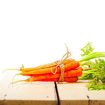 Fresh baby carrots bunch tied with rope on a rustic table