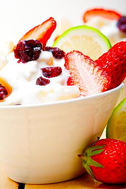 Fruit and yogurt salad healthy breakfast over white wood table