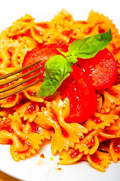 Italian pasta farfalle butterfly bow-tie with tomato basil sauce over white rustic wood table