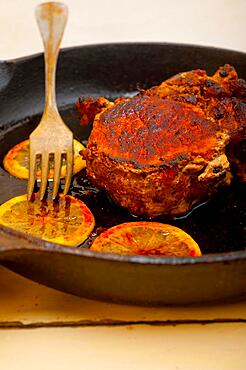 Pork chop seared on iron skillet with lemon and spices seasoning