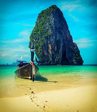 Long tail boat on tropical beach with limestone rock, Krabi, Thailand. Vintage style, cross process