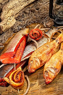 Different kinds of smoked fish and fushing net on a wooden desk