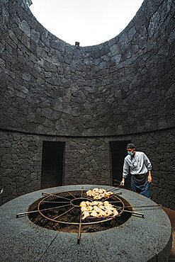 Timanfaya National Park, Spain, April 24, 2022: Cook grilling chicken on volcanic heat in El Diablo restaurant, Europe