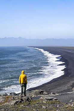 Tourist looking over long black sand beach, Reynisfjara Beach, South Iceland, Iceland, Europe