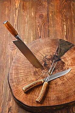 Overhead view of cleaver, fork and knife on wooden stump