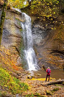 Woman in red at the waterfall in autumn, Zillenhausen, Swabian Alb, Germany, Europe