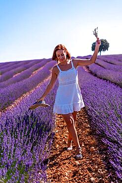 Lifestyle of a woman smiling in a summer lavender field wearing a white dress