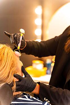 Latin ethnic woman in a beauty shop working with the client's eyebrows, massaging