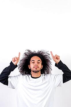 Pointing above a copy paste space. Young man with afro hair on white background