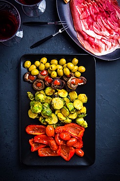 Assortment of appetizers and tapas with red wine on black background