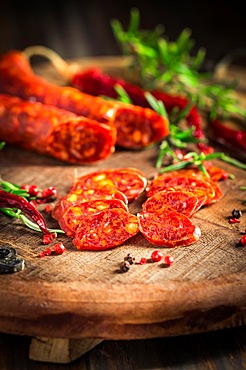 Red Spanish chorizo sausage with herbs and spices on wooden cutting board