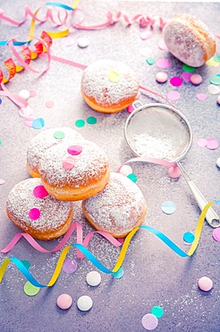 Traditional Berliner for carnival and party. German Krapfen or donuts with streamers and confetti. Colorful carnival or birthday image