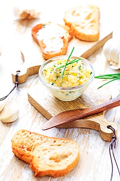 Homemade garlic butter with herbs and chives and fresh roasted baguette with salt