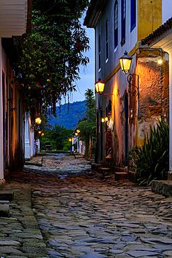 Dusk view of the city of Paraty with its old colonial style houses, lanterns and the brightness and colors of the city lights reflected in the cobbled streets, Brasil