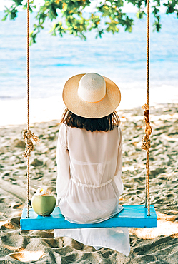 Back view of happy woman relax on swing on beautiful paradises beach. Relax and vacation concept