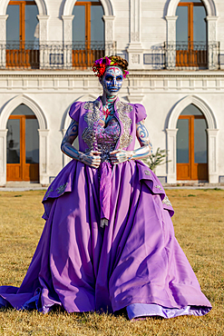 A gorgeous Hispanic Brunette model poses with traditional skull sugar makeup paint for a Mexican festival