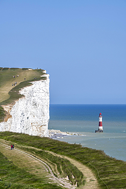 Tourists walking along the chalk cliffs overlooking Beachy Head lighthouse, South Downs, East Sussex, England, United Kingdom, Europe