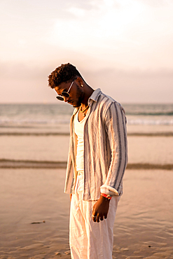 Portrait of black ethnic man enjoying summer vacation by the sea at sunset