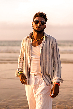 Portrait of attractive black ethnic man enjoying summer vacation by the sea at sunset