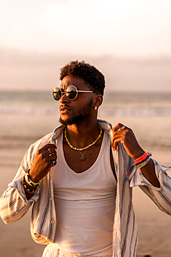 Portrait of attractive black ethnic man enjoying summer vacation by the sea at sunset