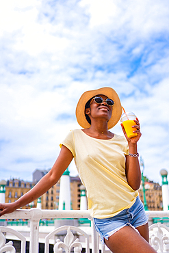 Portrait of black ethnic woman having an orange juice enjoying the summer