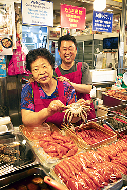 Korean woman and Korean man with a crab, Gwangjang market, traditional street market in Jongno-gu, Seoul, South Korea, Asia