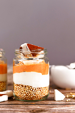 Layered breakfast or dessert with puffed quinoa grains, yogurt and coconut flakes and pieces in glasses