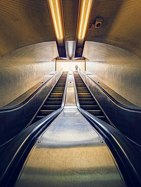 Lone man climbing out on a subway escalator. Symmetrical underground moving staircase