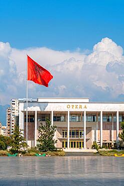 Palace of Culture or Opera on Skanderbeg Square in Tirana and the flag of Albania moving in the wind