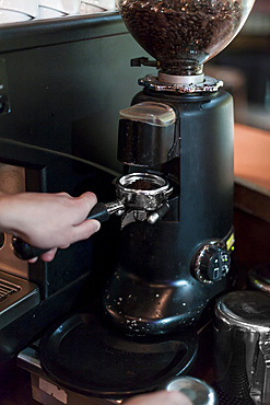 Crop hands grinding coffee into portafilter