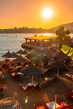 Beautiful resort with umbrellas and palm trees by the sea at sunset in Sarande or Saranda on the Albanian riviera, Albania, Europe