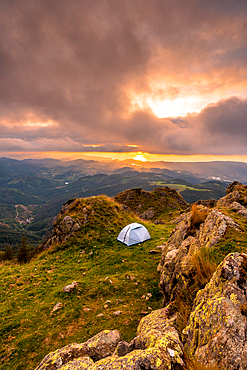 Wild camping on the top of a mountain at sunset, sleeping in the open air after the long trek in the mountains