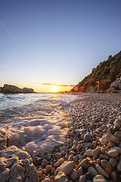 Hidden bay on the Mediterranean at sunrise. Look at the small beach of sand and pebbles, the beach is bathed in warm colours of the dawn in the morning. View of the sea at Xigia Sulfur Beaches, Zakynthos, Ionian Islands, Greece, Europe