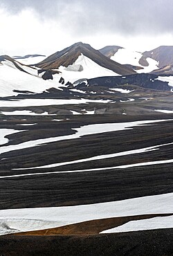 Dramatic volcanic landscape with mountains and snow, at Höskuldsskáli hut in Hrafntinnusker, Laugavegur trekking trail, Landmannalaugar, Fjallabak Nature Reserve, Suðurland, Iceland, Europe