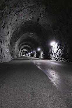 Interior view of an illuminated tunnel with rock faces and asphalt road, Zillertal, Austria, Germany, Europe