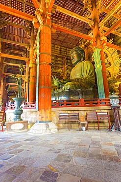 Side profile of Daibutsu bronze Buddha and ceiling of inside the Great Buddha Hall, Daibutsuden at Todai-ji temple in Nara, Japan. Vertical interior