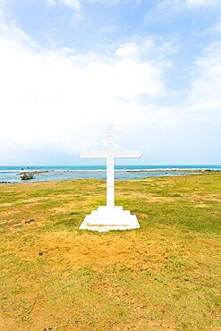 White cross is planted outside of Saint Thomas Church along the ocean in Point Pedro, Jaffna, Sri Lanka. Vertical