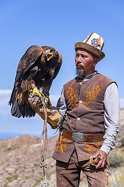 Traditional Kyrgyz eagle hunter with eagle in the mountains, near Kysyl-Suu, Kyrgyzstan, Asia