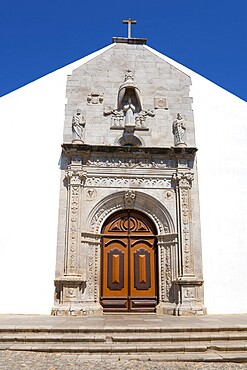 Historic church façade with detailed stonework and wooden door under a blue sky, Igreja da Misericórdia, Church of Mercy, Art Museum, Tavira, Faro, Algarve, Portugal, Europe