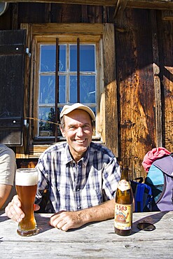 Husband drinking wheat beer, having a break from a mountain hike, mountain pasture, Mitterhuettet cabin, Alps, Germany, Europe